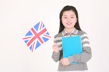 A girl holing up a Union jack and book - isolated on whiteの写真素材