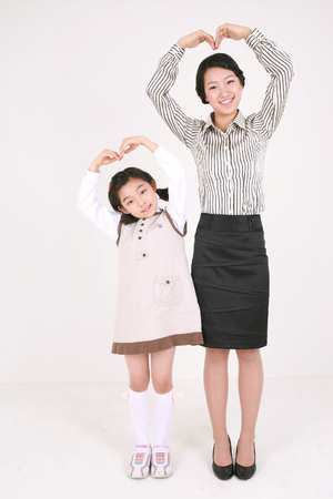An asian girl and a woman stading with smile - isolated on whiteの写真素材