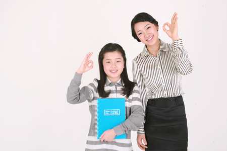 A female teacher and girl gesturing okay - isolated on whiteの写真素材