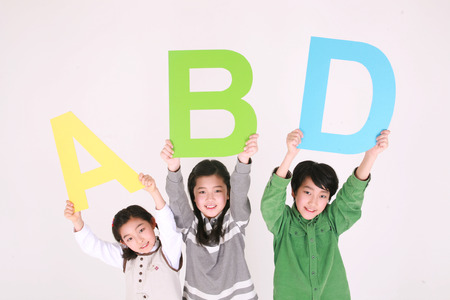 Asian kids holding up alphabet shaped signs - isolated on whiteの写真素材