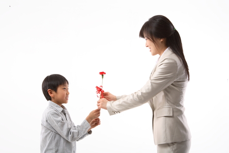 An asian boy handing over a flower to a teacher - isolated on whiteの写真素材