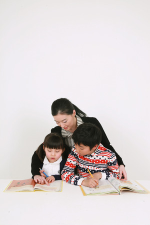 A female teacher and two kids studying