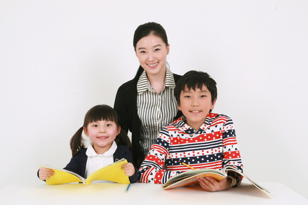 A female teacher and two kids studyingの写真素材