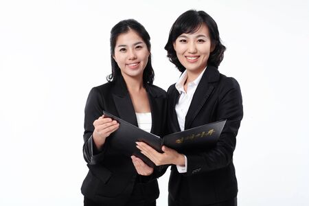 Two Asian business women posing in the studio - isolated on whiteの写真素材