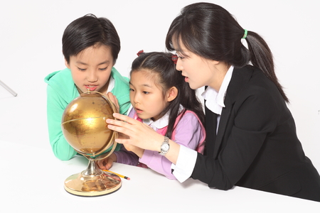 A female teacher and a little girl looking at a globe - isolated on whiteの写真素材