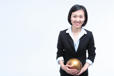 Young Asian businesswoman posing with golden globe - isolated on whiteの写真素材