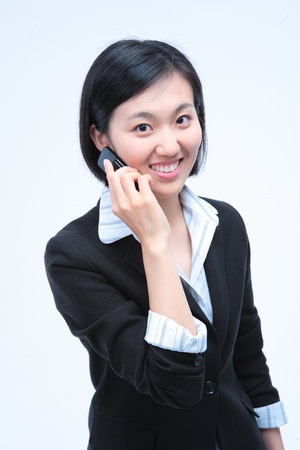 Young Asian businesswoman posing with a cellphone - isolated on whiteの写真素材