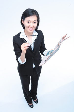 Young Asian businesswoman posing with newspaper and glasses - isolated on whiteの写真素材
