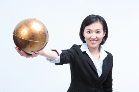 Young Asian businesswoman posing with golden globe - isolated on whiteの写真素材