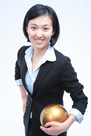 Young Asian businesswoman posing with golden globe - isolated on whiteの写真素材