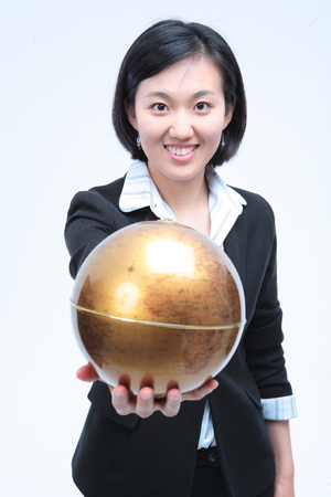 Young Asian businesswoman posing with golden globe - isolated on whiteの写真素材