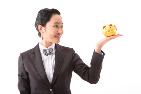 Asian businesswoman posing with a golden piggy bank - isolated on whiteの写真素材