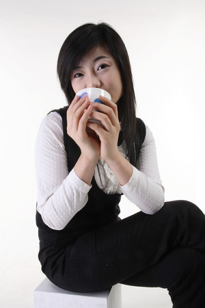 Young Asian girl in tuxedo drinking on the table - isolated on whiteの写真素材