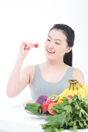 Young Asian woman with healthy vegetables and fruits - isolated on whiteの写真素材