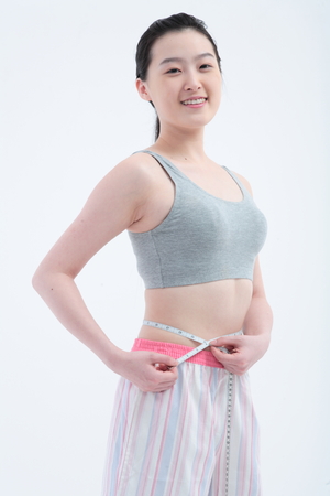 Young Asian woman with measure tape - isolated on whiteの写真素材