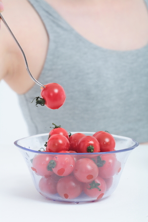 Young Asian woman with cherry tomatoes - isolated on whiteの写真素材