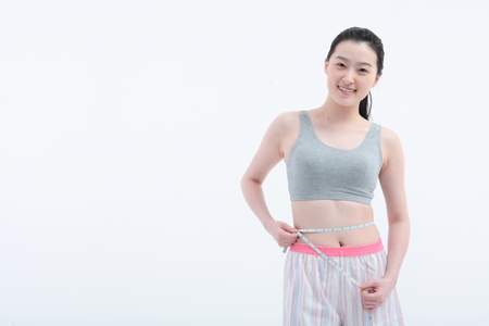 Young Asian woman with measure tape - isolated on whiteの写真素材