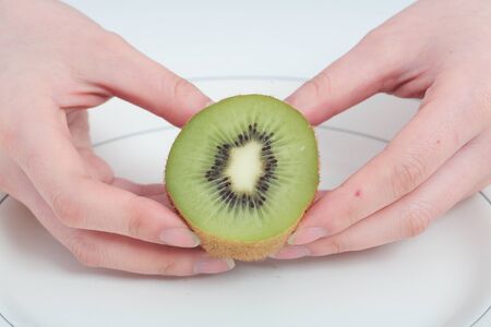 Young Asian woman with kiwi fruit - isolated on whiteの写真素材