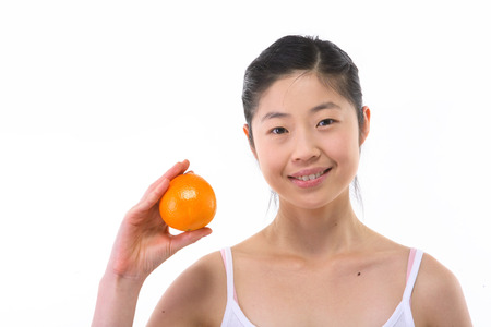 Young Asian woman posing with a fresh orange - isolated on whiteの写真素材
