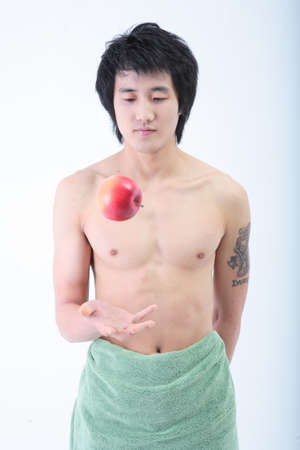 Diet Concept - Topless Asian man wrapped in towel posing with an appleの写真素材