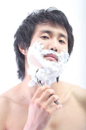 Topless Asian man shaving - isolated on whiteの写真素材