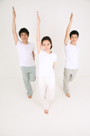 Young Asian people doing yoga poses together - isolated on whiteの写真素材