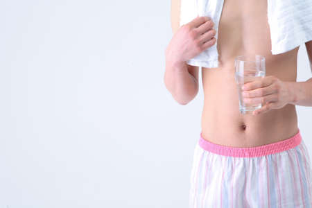 Diet Concept - Topless Asian man posing with a glass of waterの写真素材