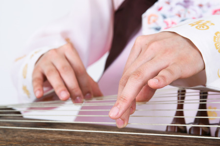 Asian woman with traditional clothing playing musical instrument - isolated on whiteの写真素材
