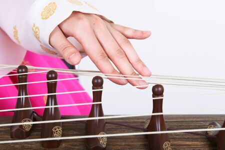 Asian woman with traditional clothing playing musical instrument - isolated on whiteの写真素材