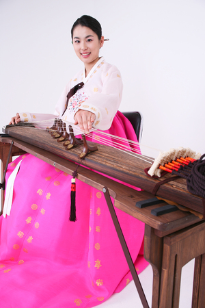 Asian woman with traditional clothing playing musical instrument - isolated on whiteの写真素材