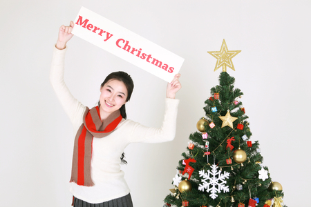 Young korean woman beside christmas tree - isolated on whiteの写真素材