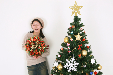 Young korean female student beside christmas tree - isolated on whiteの写真素材