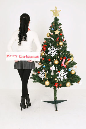 Young korean woman beside christmas tree - isolated on whiteの写真素材
