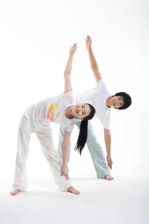 Young Asian couple working out together, doing yoga poses - isolated on whiteの写真素材