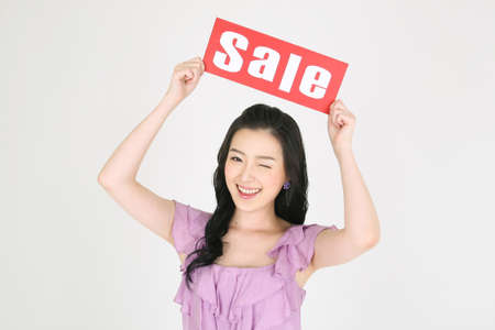 Shopping Concept - Young Asian woman posing with sale text cardの写真素材