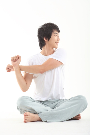 Young Asian man working out, stretching, warming up - isolated on whiteの写真素材