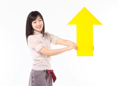 Young asian woman holding up an arrow sign in studio - isolated on white
