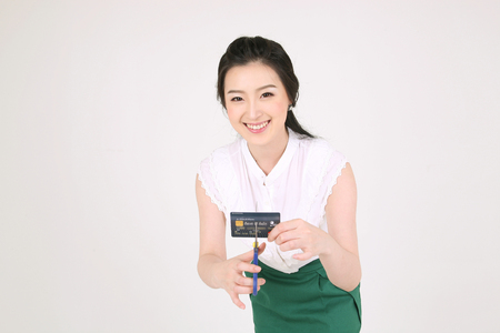 Shopping concept - Young Asian woman cutting her credit card with scissorsのeditorial素材