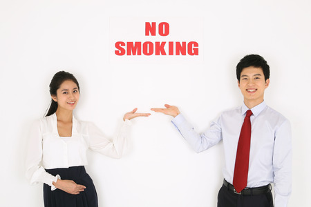 No smoking concept - Young Asian couple posing with no smoking signの写真素材