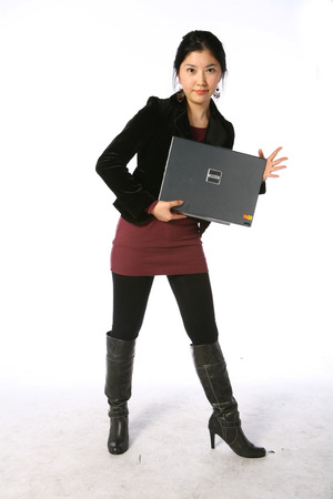 Young asian woman holding up a laptop computer in studio - isolated on whiteのeditorial素材