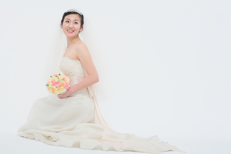 Beautiful Asian bride posing with bouquet, isolated on whiteの写真素材