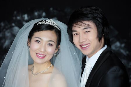 Happy Asian bride and groom posing in the studioの写真素材