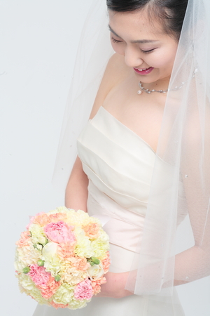 Beautiful Asian bride posing with bouquet, isolated on whiteの写真素材