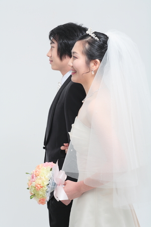 Happy Asian bride and groom posing in the studio - isolated on whiteの写真素材