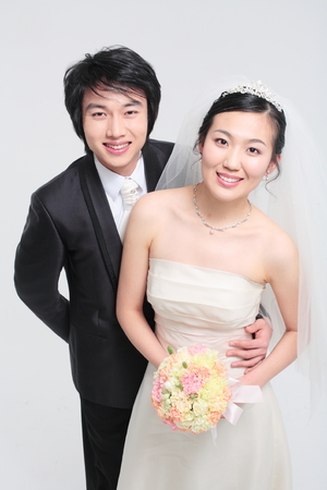 Happy Asian bride and groom posing in the studio - isolated on whiteの写真素材