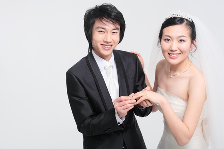 Happy Asian bride and groom posing in the studio - isolated on whiteの写真素材