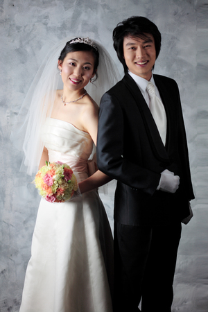 Happy Asian bride and groom posing in the studioの写真素材