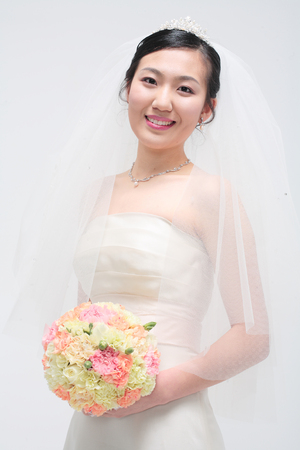 Beautiful Asian bride posing with bouquet, isolated on whiteの写真素材