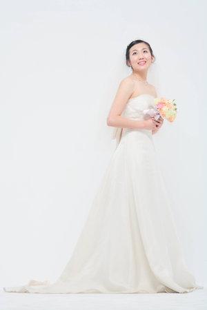 Beautiful Asian bride posing with bouquet, isolated on whiteの写真素材