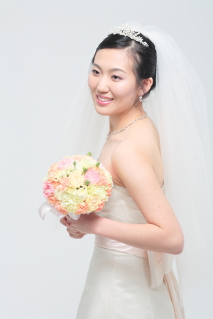Beautiful Asian bride posing with bouquet, isolated on whiteの写真素材